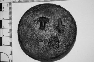 Lead merchant pan weight stamped with three emblems: a Roman numeral “I” surmounted by a crown, the sword of St. Paul, and the “angel and scales.”  (Photo: INA). REF4442